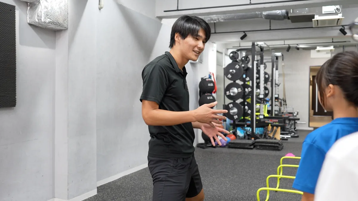 ラダーを使ったドリルを笑顔で説明するコーチ