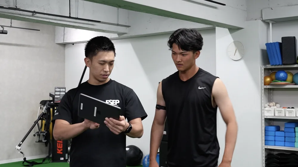 タブレットで選手の状態を確認しながら説明するトレーナー